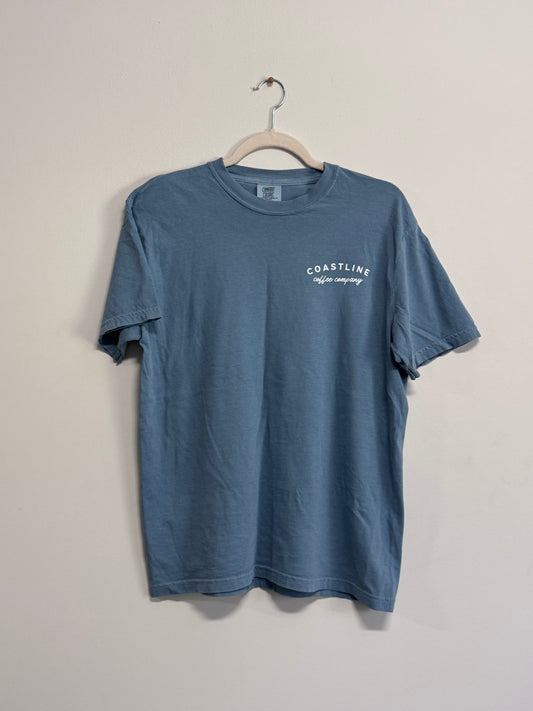 Blue t-shirt with 'Coastline Coffee Company' logo on a hanger against a plain background